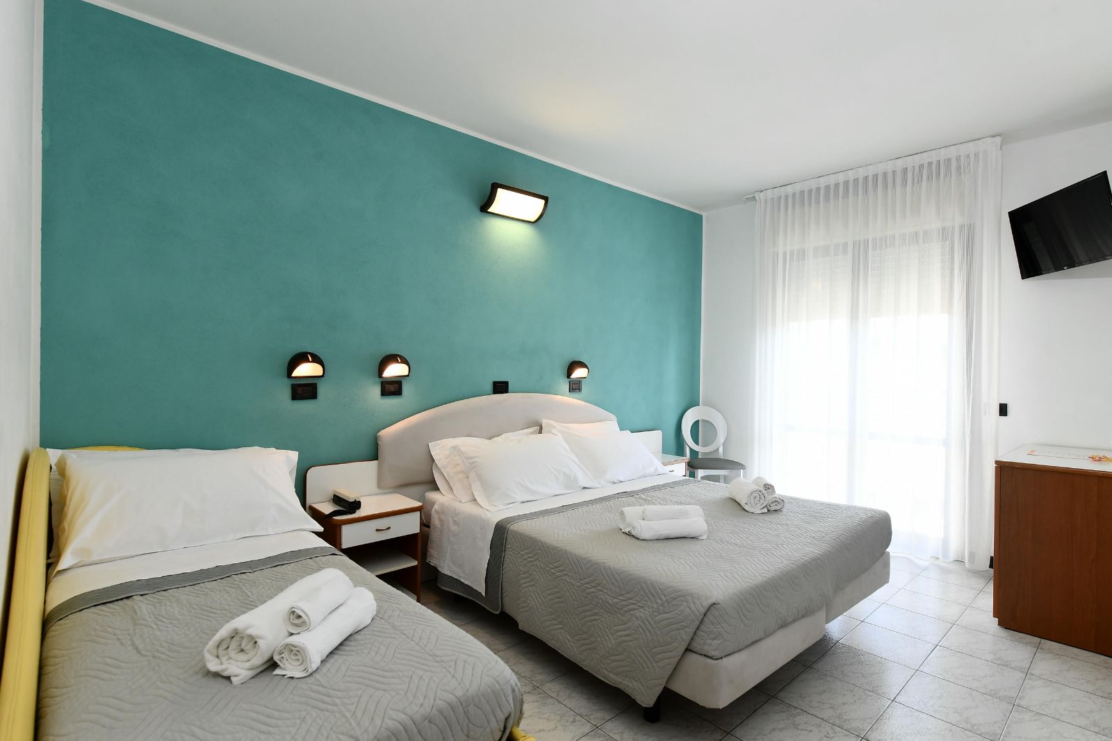 Camera Comfort dell'Hotel Criniera d'Oro con parete verde acqua e luce naturale